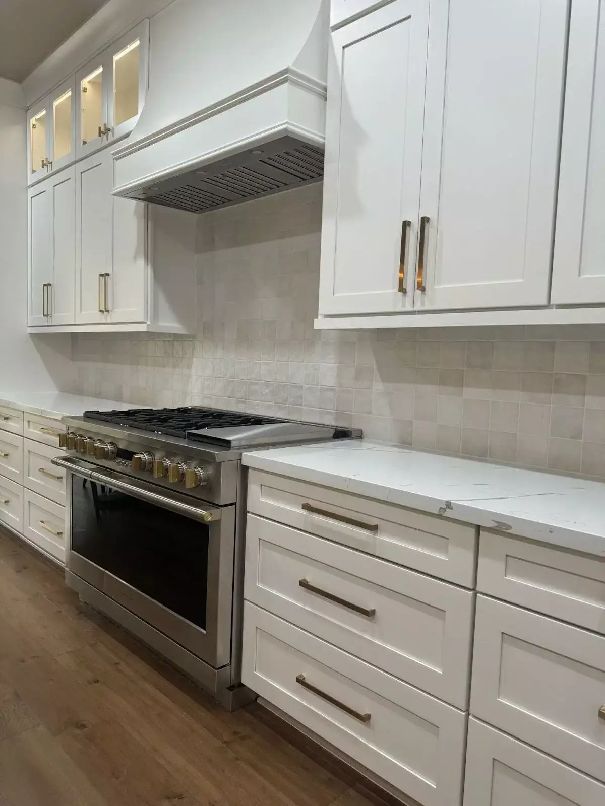 Modern kitchen with a stainless steel gas stove, white shaker cabinets, and a minimalist tile backsplash.
