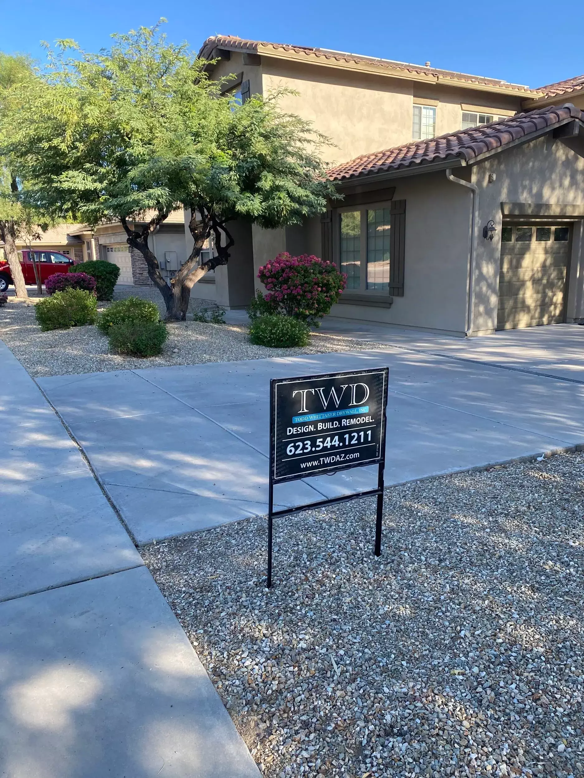 Exterior of a professionally remodeled home in Arizona with a TWD (Todd Whittaker Drywall Inc.) sign showcasing design, build, and remodel services.