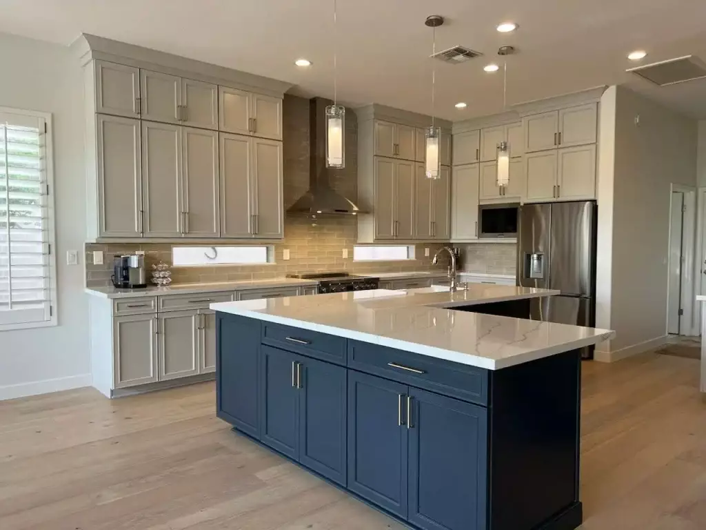 Modern Phoenix kitchen with light gray upper cabinets, navy blue island, quartz countertops, stainless steel appliances, and pendant lighting.