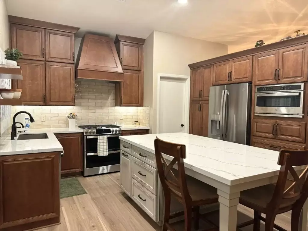 Traditional-style kitchen with warm wood cabinetry, stainless steel appliances, and a white quartz-topped island with seating for two.