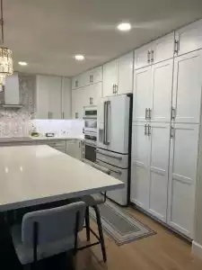 Elegant Arizona kitchen design featuring integrated appliances, custom white cabinetry, and a waterfall-edge quartz island for a clean, cohesive aesthetic.